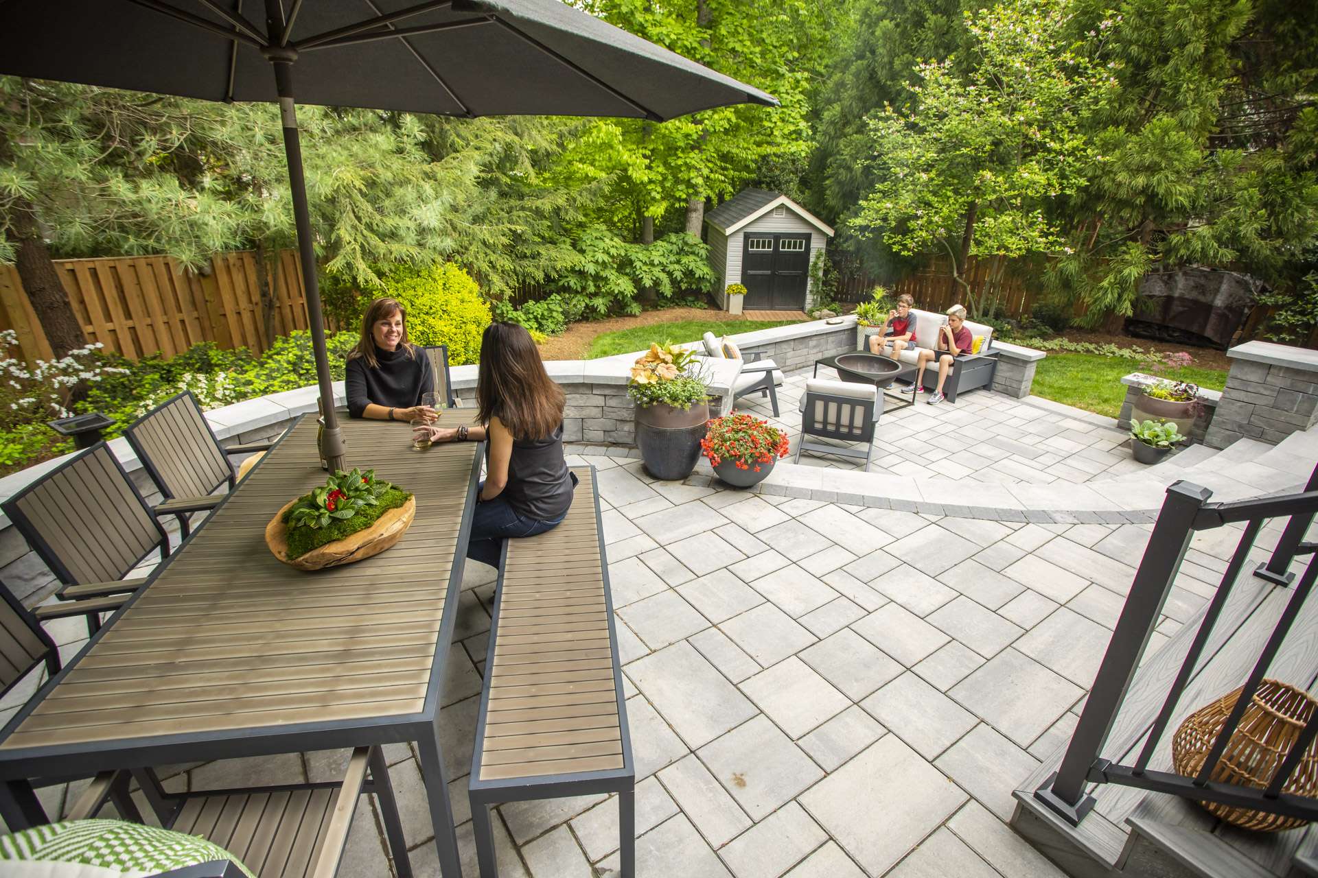 two-tiered patio with dining table and fire pit