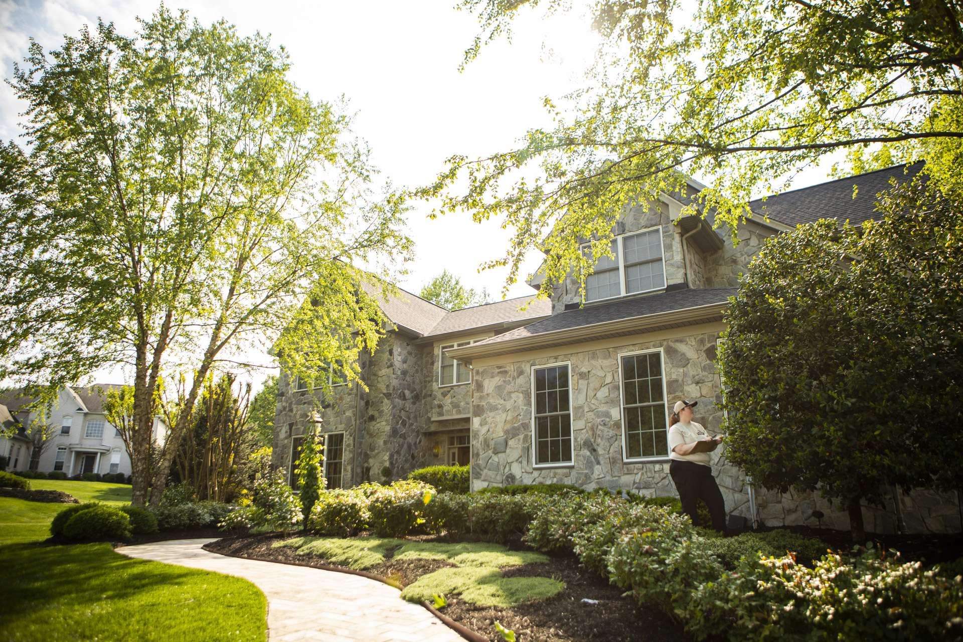 landscape maintenance technician inspecting shrubs and trees