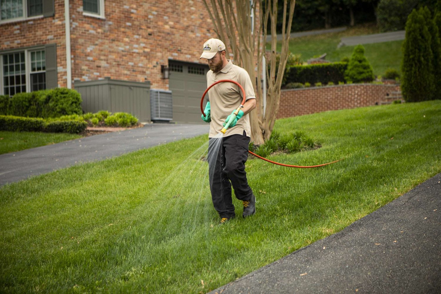 Lawn care technician spraying lawn to maintain healthy grass