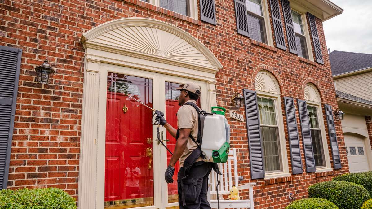 pest control team sprays home near front door