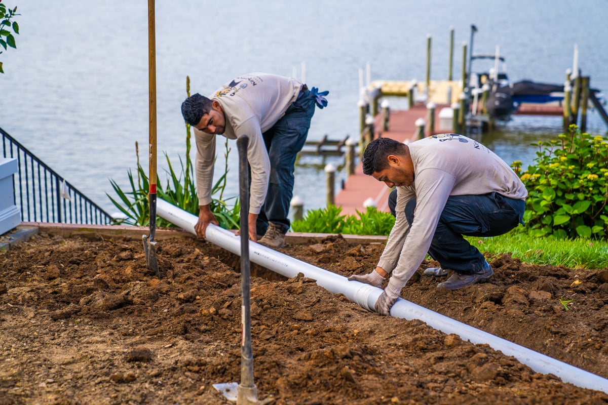 landscape technicians installing a solid drain pipe