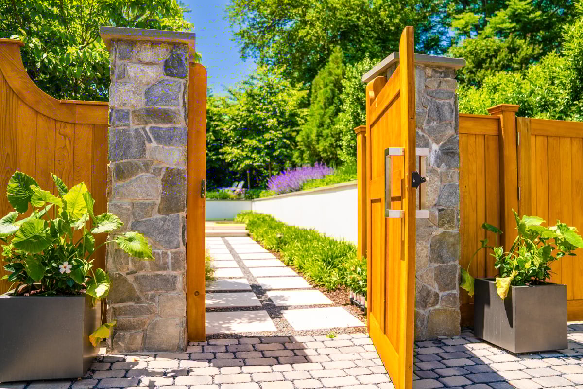 paver driveway leading to gate with plantings and stepping stone entrance