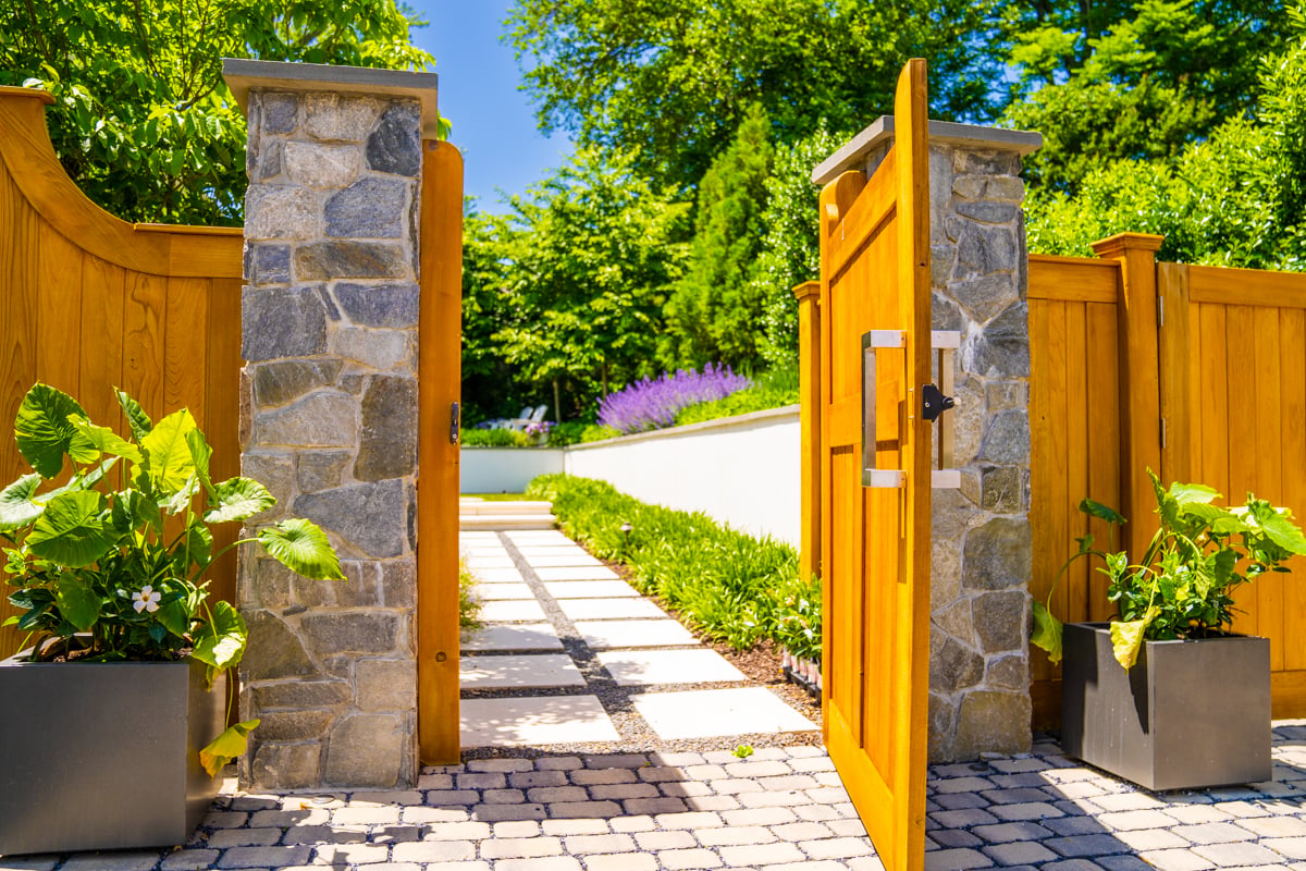 paver driveway leading to gate with plantings and stepping stone entrance