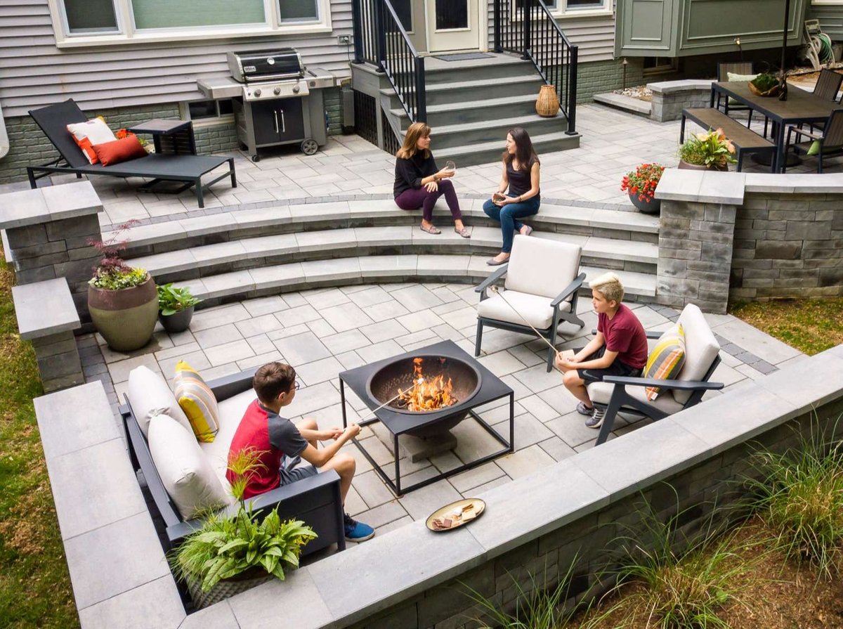 family sits on patio with retaining wall and firepit