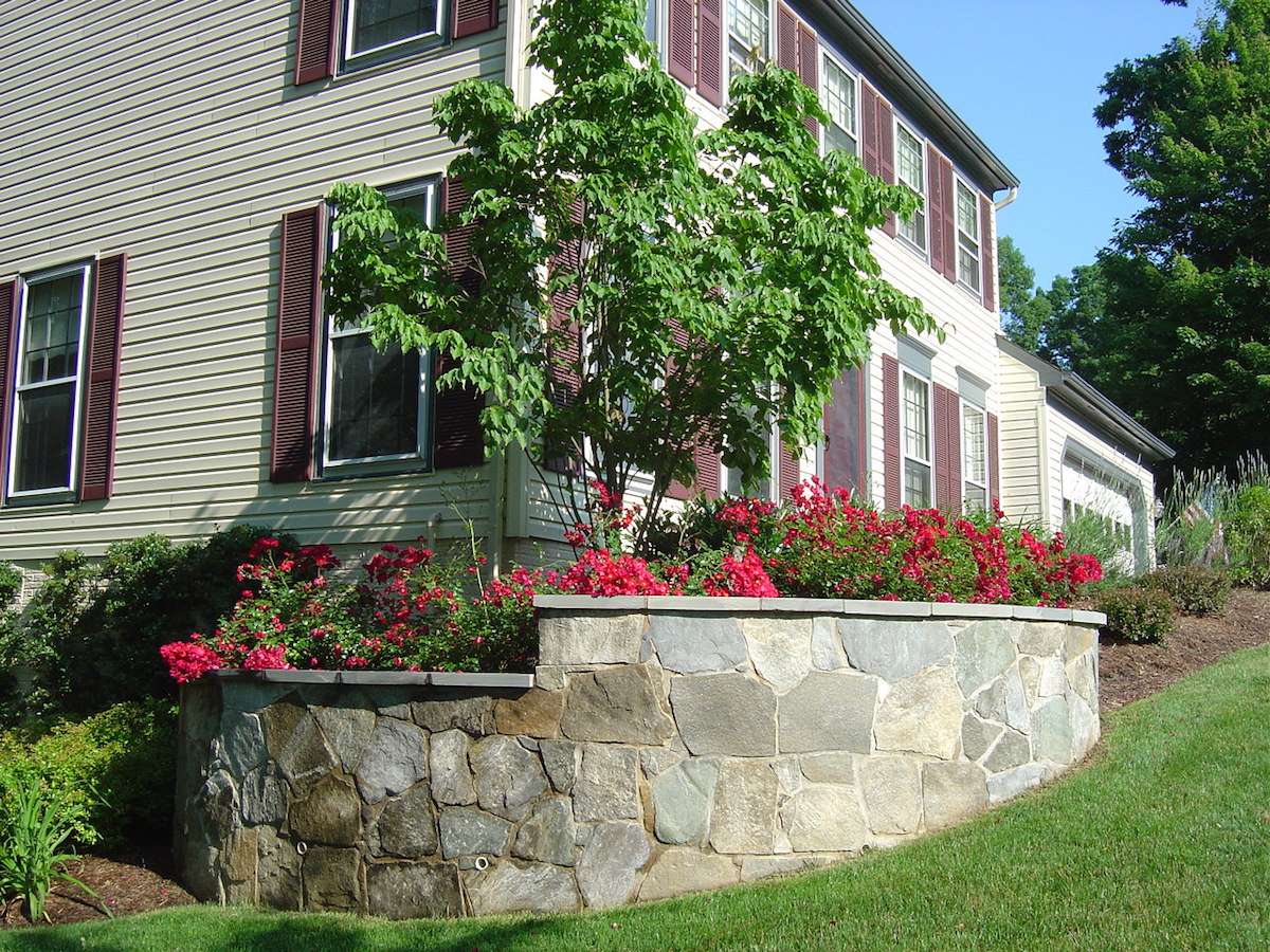 stone retaining wall in front of home with plantings