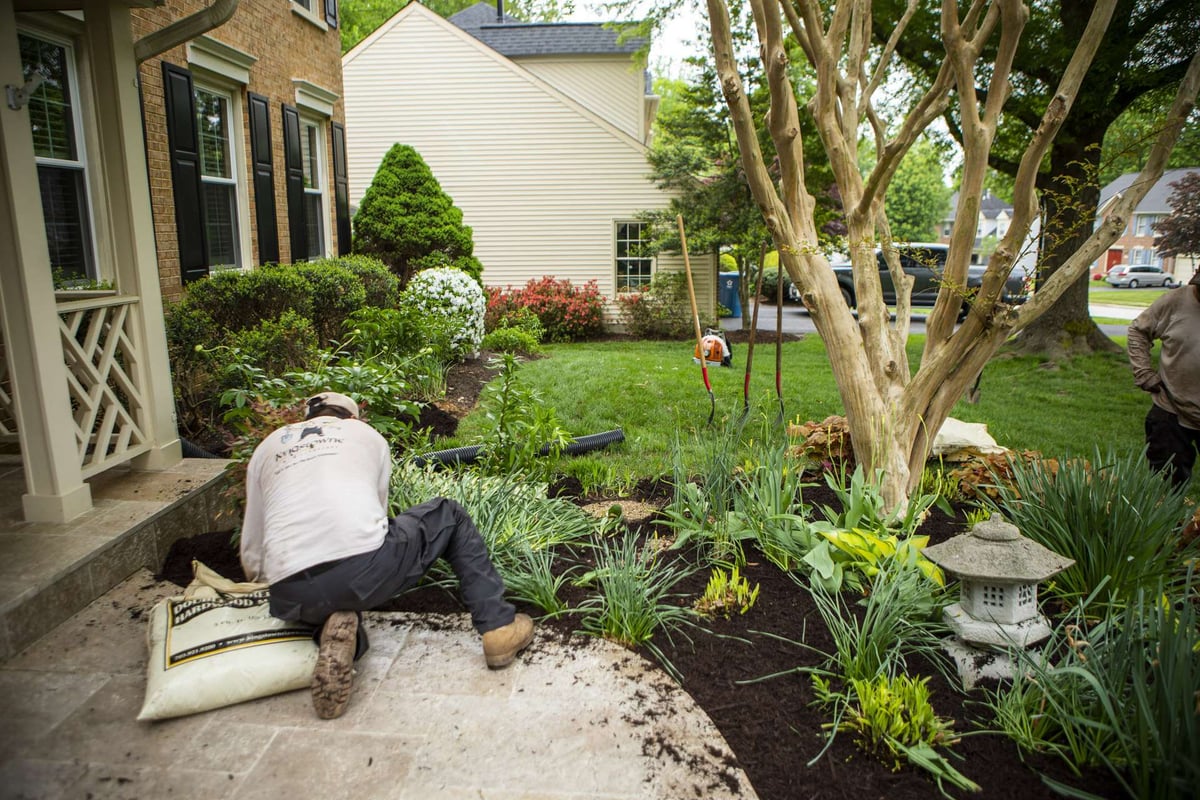 landscape maintenance team mulches flower bed