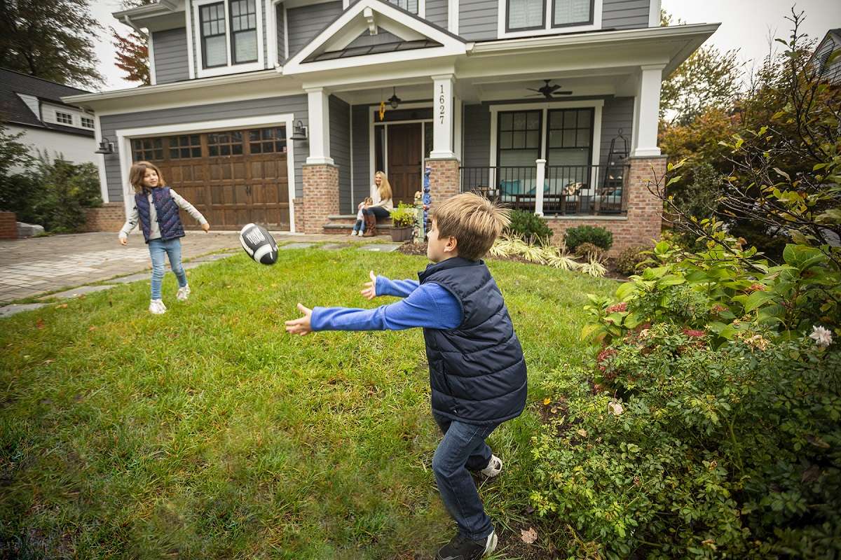 children playing catch with football in front yard of home