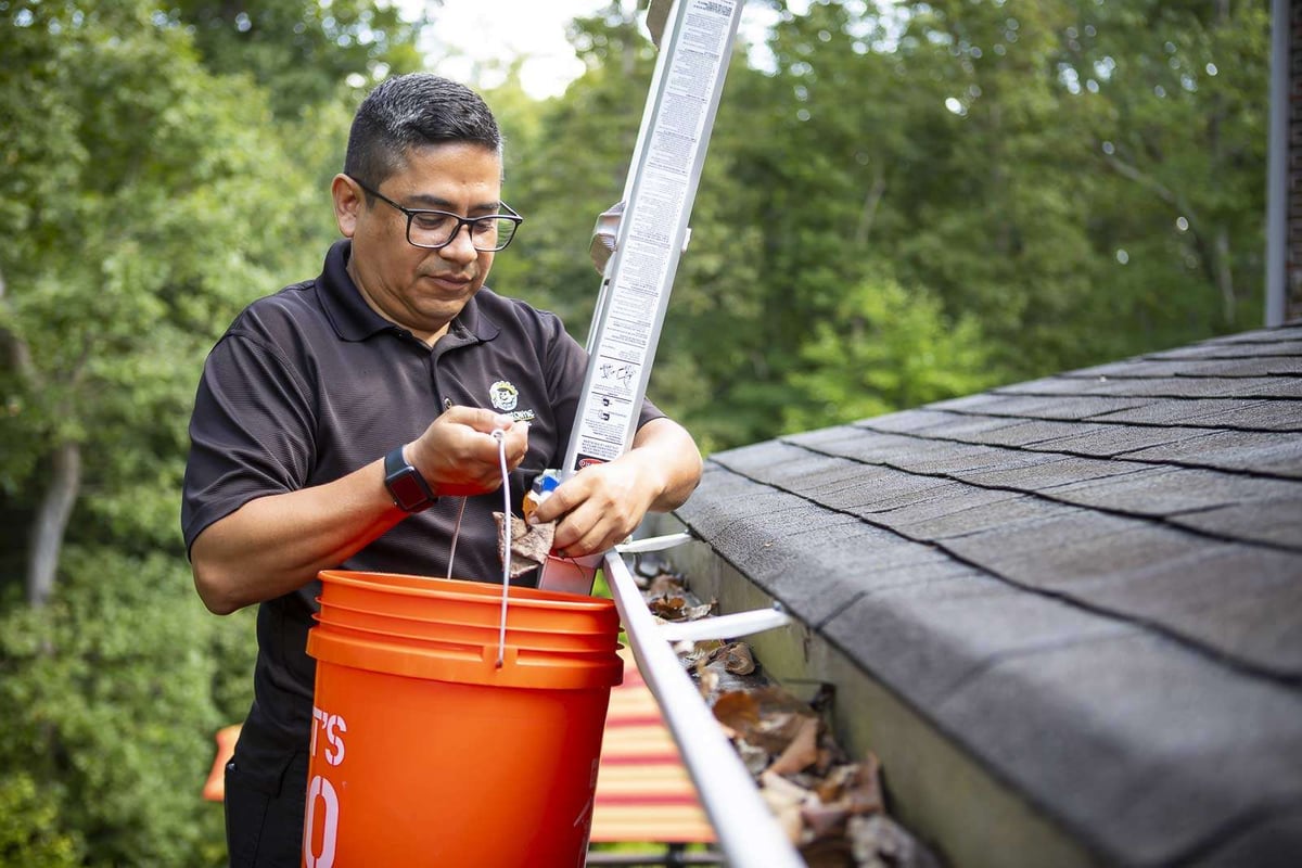 landscape team member cleans leaves out of gutter