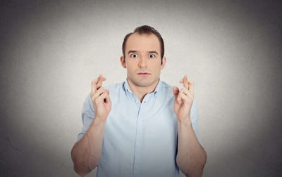 Man with fingers crossed hoping that he did his lawn care correctly