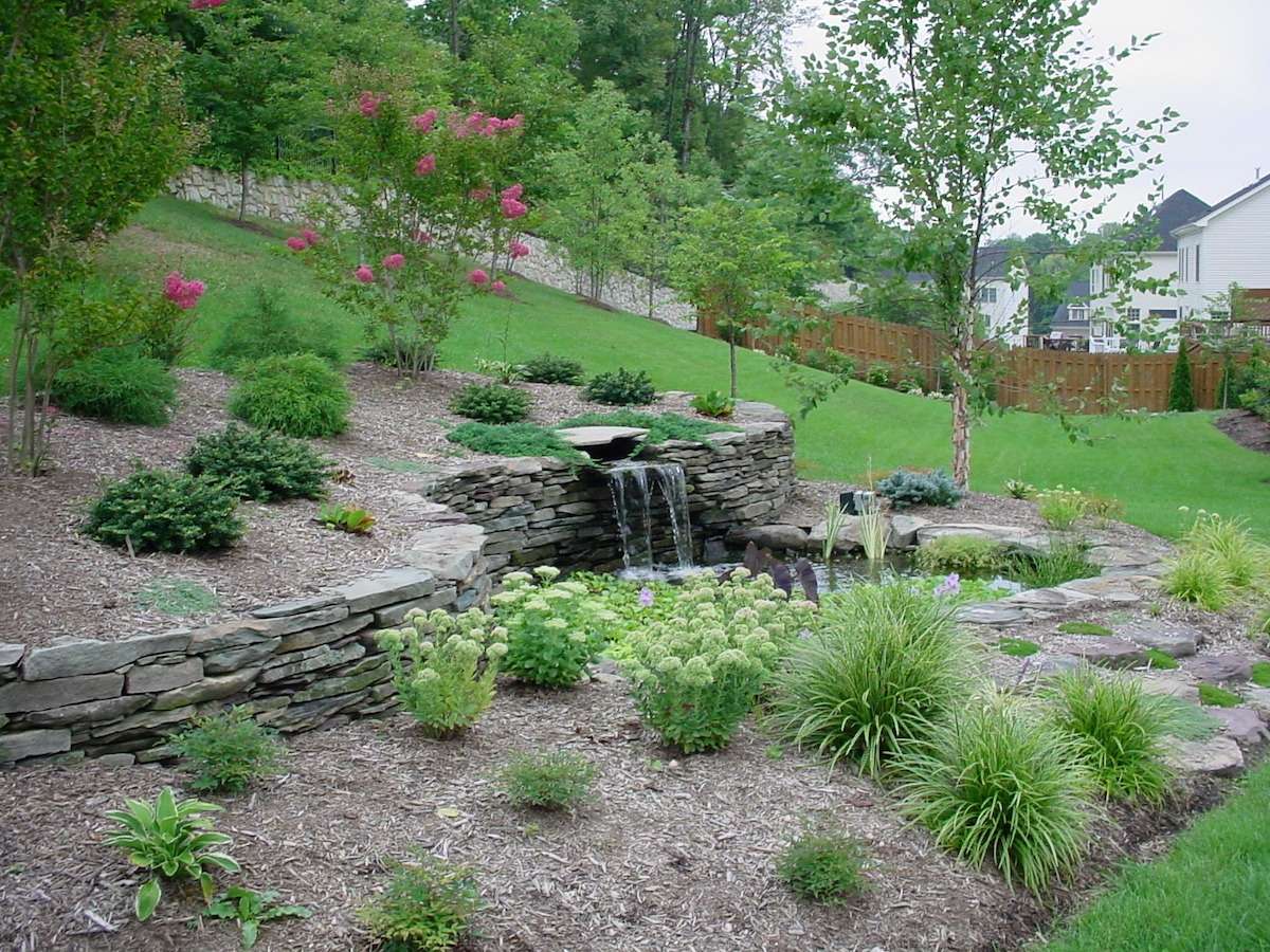 stone retaining wall with water feature and plantings