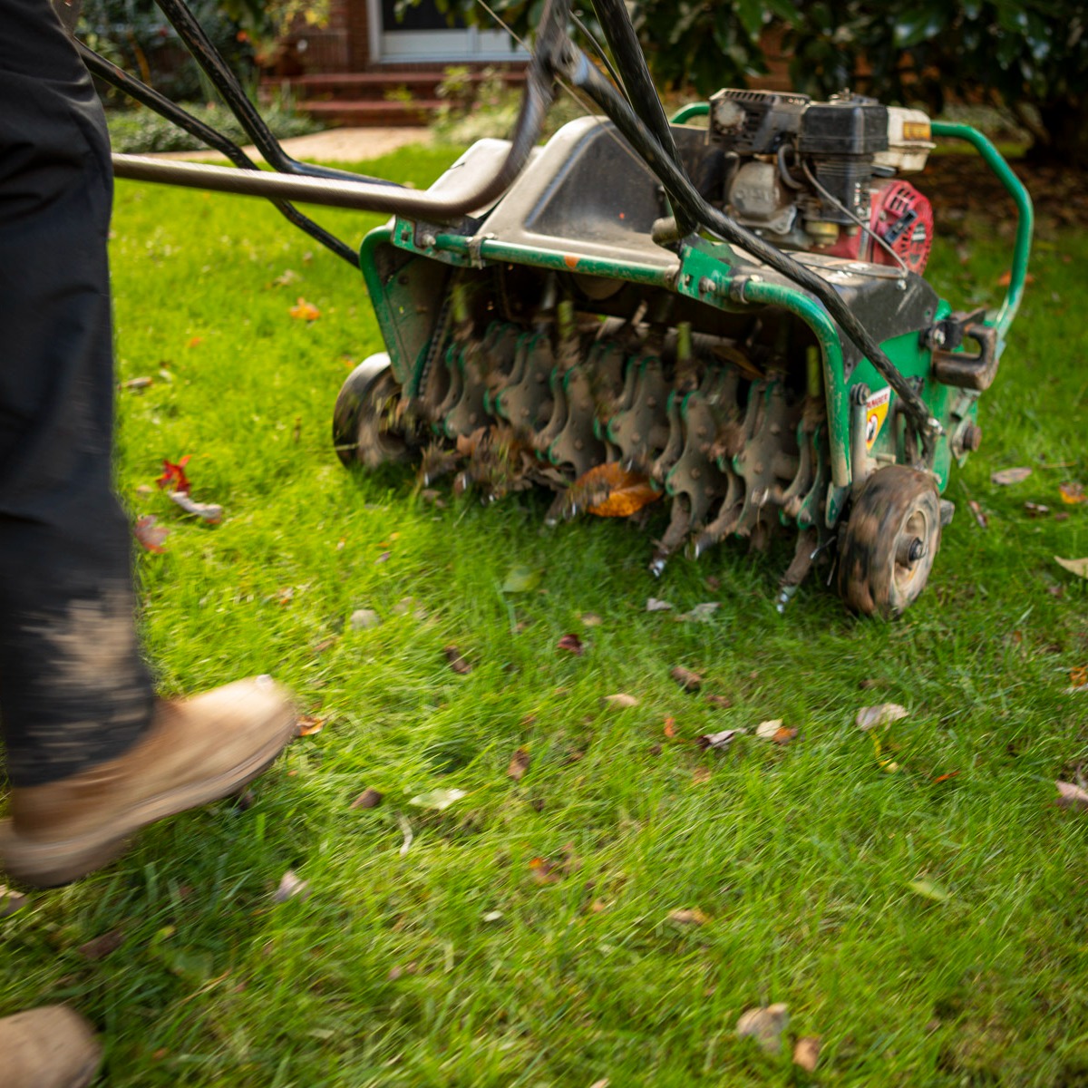 lawn care technician running a walk behind lawn aerator