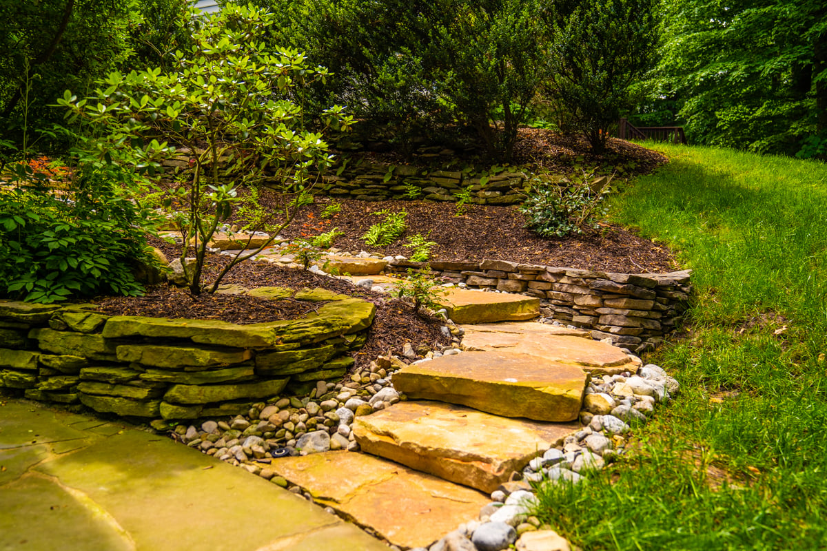 natural stone steps set into hillside hardscape with planting beds