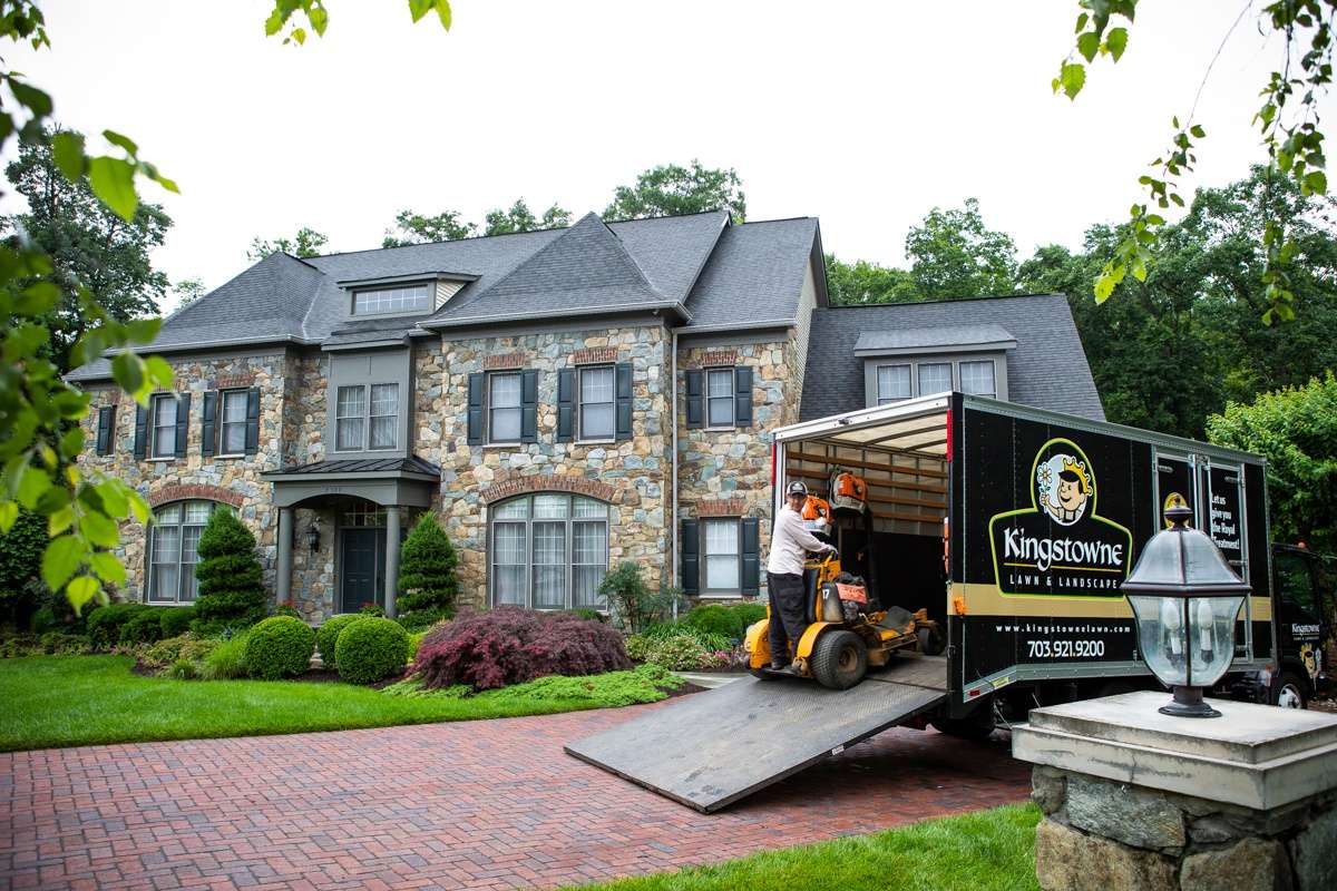 lawn care team unloads equipment from truck in front of home