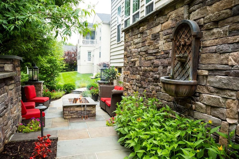 patio with wall, fountain, and fire pit designed by Kingstowne Lawn & Landscape