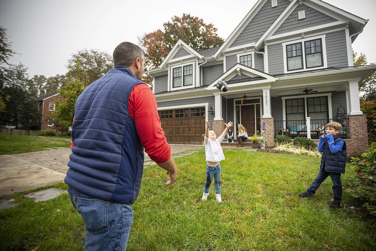 family playing in yard in front of home