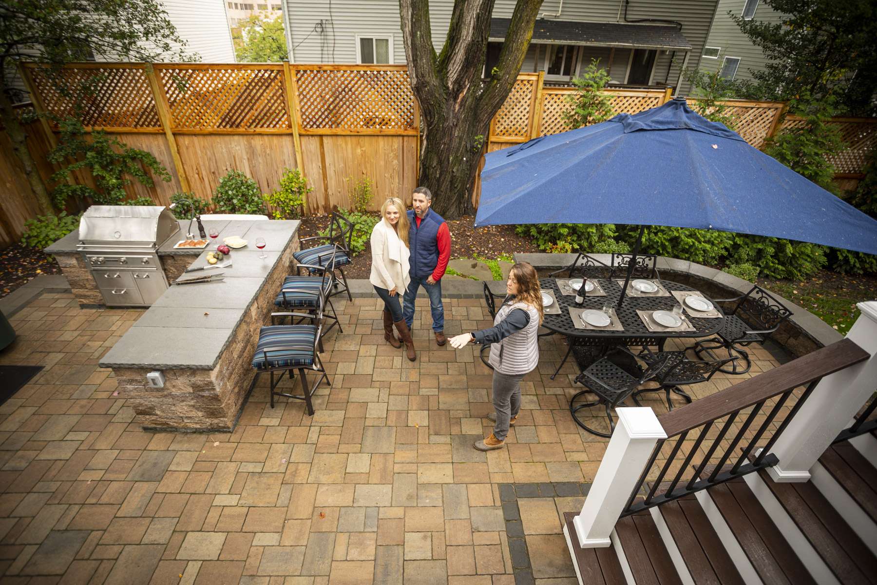 people on paver patio with outdoor kitchen in small backyard