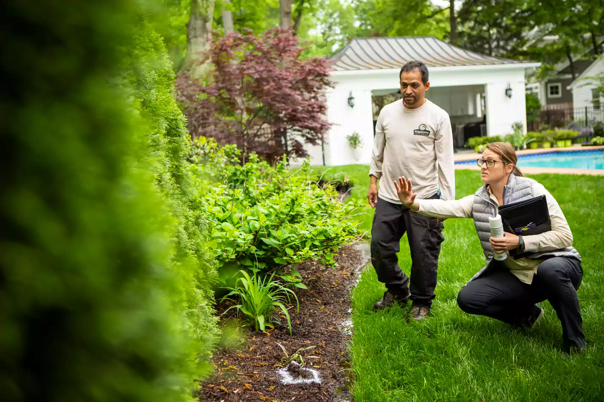 landscape maintenance account manager and technician inspecting garden plants for signs of pest and plant disease