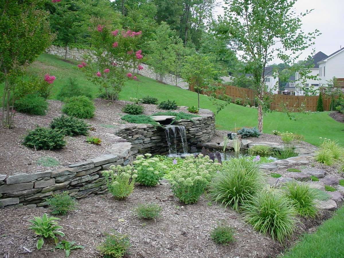 landscape bed with several plantings and waterfall