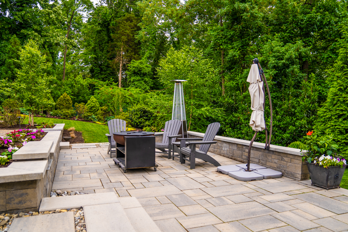 hardscape patio and retaining wall with lawn furniture and border plantings on a sloped backyard