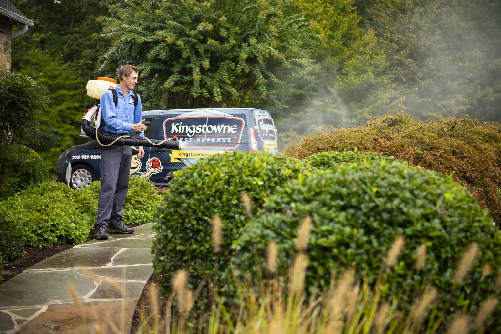 pest control technician sprays landscape beds for mosquitoes